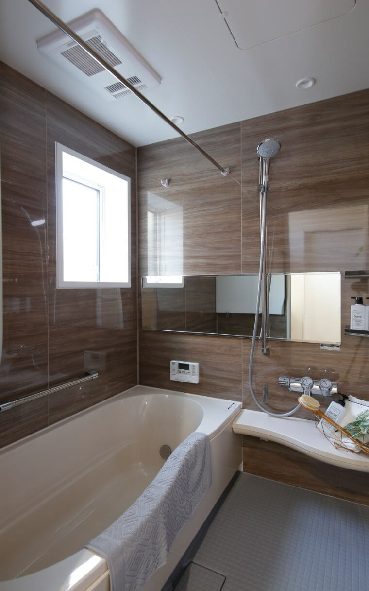 疲れた心をほぐす木目調の浴室。鏡を横長にすることで空間に奥行をもたらし、広々としたバスルームを演出しています。